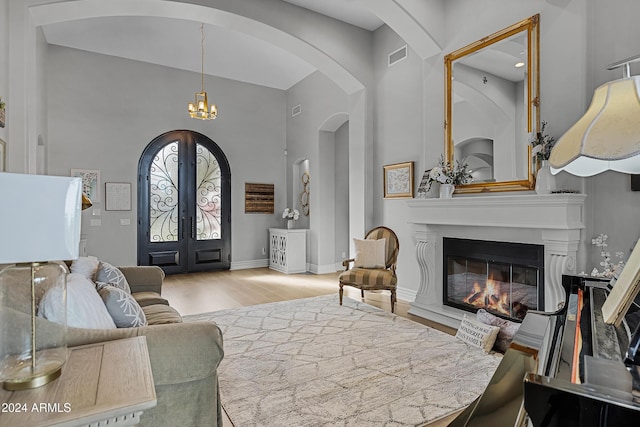 living room with french doors, a chandelier, and light hardwood / wood-style flooring