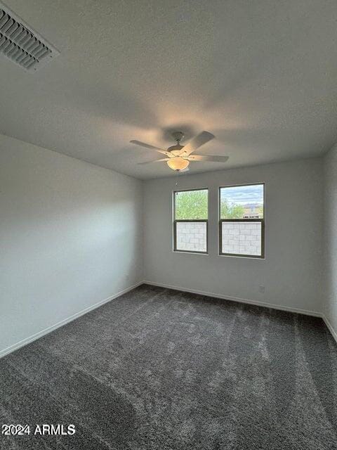 unfurnished room featuring a textured ceiling and dark carpet