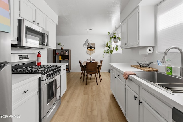 1111 E Turney Ave Unit 3, Phoenix, AZ 85014 - kitchen with stainless steel appliances, a sink, light countertops, white cabinetry, and light wood finished floors