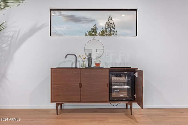 bar featuring wine cooler and light hardwood / wood-style floors