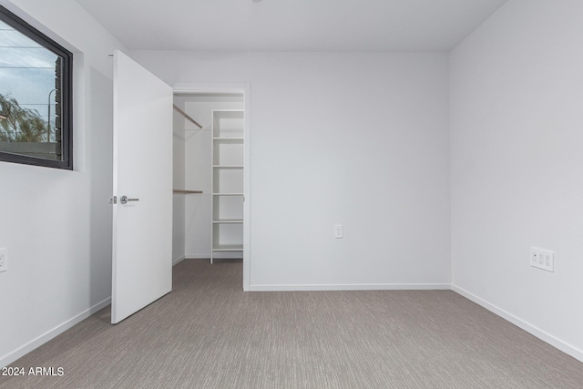 unfurnished bedroom with a walk in closet, light carpet, and a closet