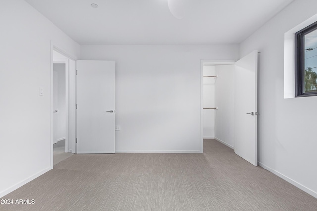 unfurnished bedroom featuring light carpet and a spacious closet