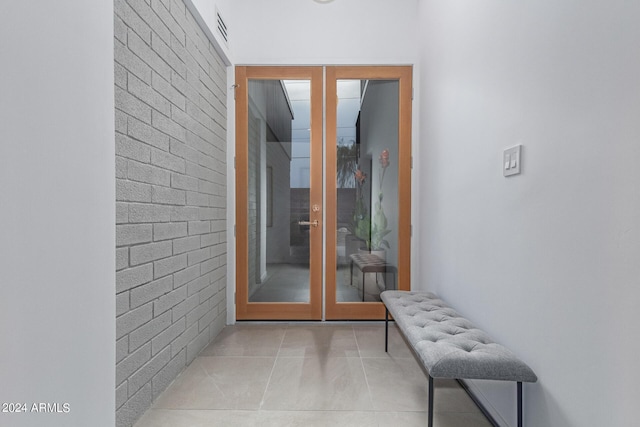 entryway with light tile patterned flooring, french doors, and brick wall