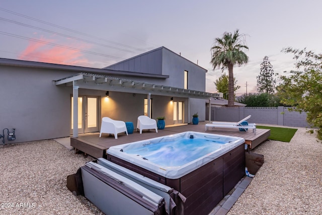 pool at dusk with a pergola, a hot tub, and a deck