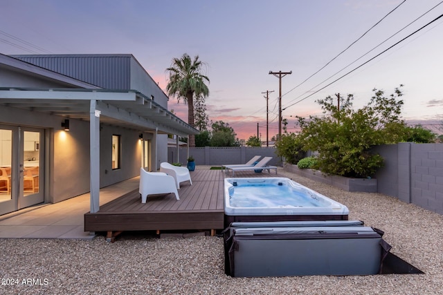 pool at dusk featuring a wooden deck and a covered hot tub