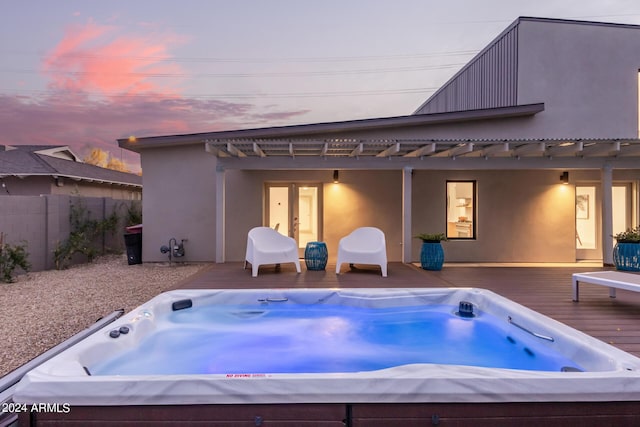 back house at dusk featuring an outdoor hot tub and a deck