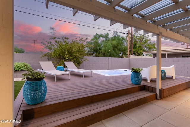 deck at dusk with an outdoor hot tub and a pergola