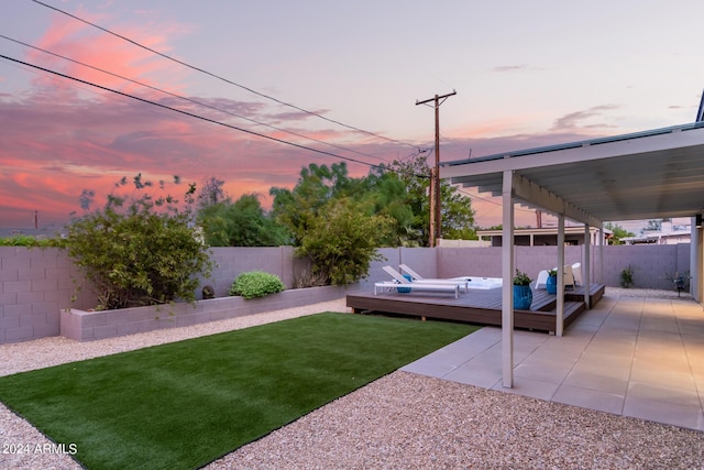 yard at dusk featuring a deck and a patio area