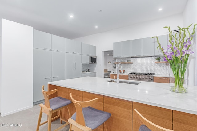 kitchen featuring a breakfast bar, tasteful backsplash, sink, stove, and light stone counters