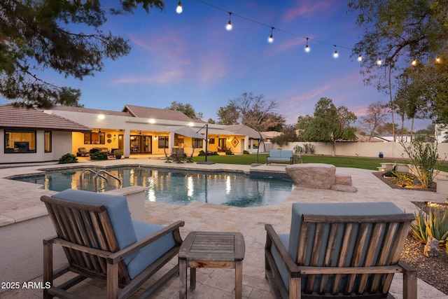 pool at dusk with a patio area, outdoor lounge area, and a yard