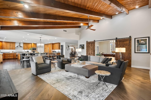 living room with dark wood-type flooring, ceiling fan, a barn door, beamed ceiling, and wood ceiling