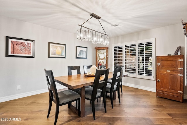 dining space featuring hardwood / wood-style floors and an inviting chandelier