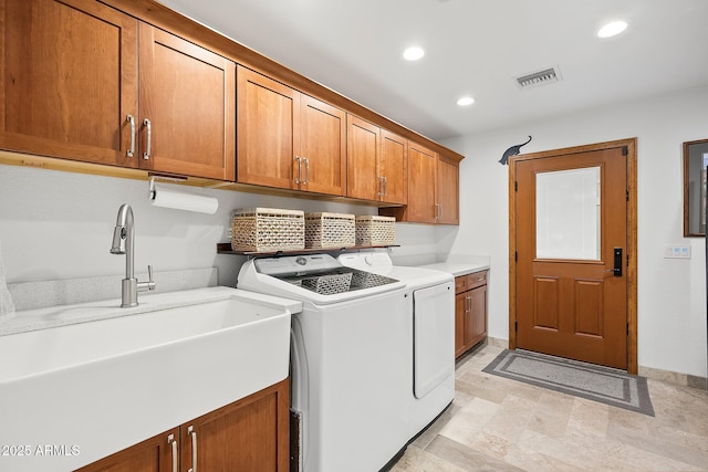 clothes washing area featuring washer and dryer, sink, and cabinets