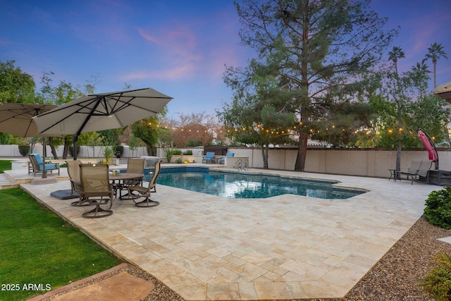 pool at dusk with a patio area