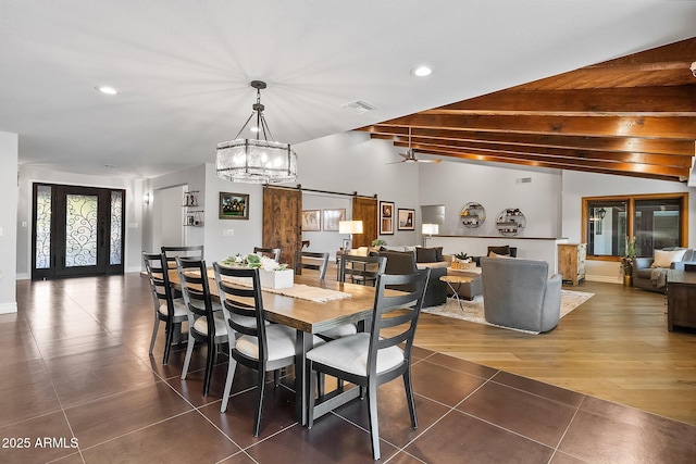 dining room featuring ceiling fan with notable chandelier, dark hardwood / wood-style flooring, a barn door, and vaulted ceiling