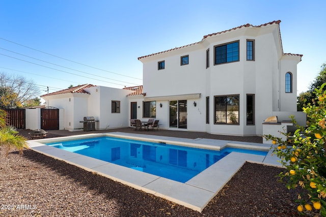 back of house with a fenced in pool and a patio