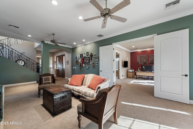 carpeted living room with crown molding and ceiling fan