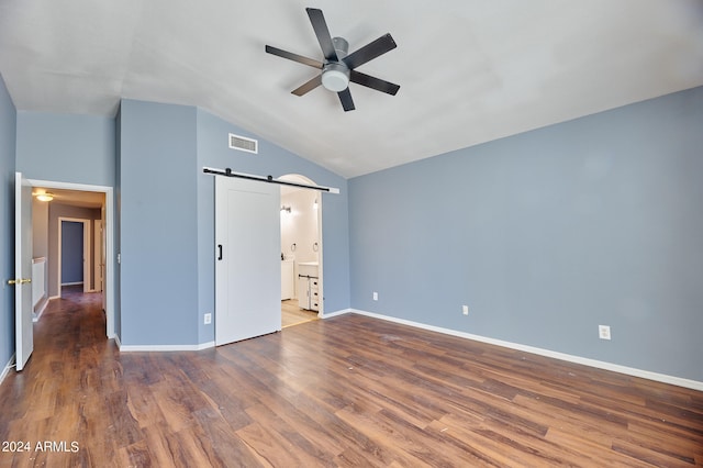 unfurnished bedroom with ceiling fan, vaulted ceiling, dark wood-type flooring, and a barn door