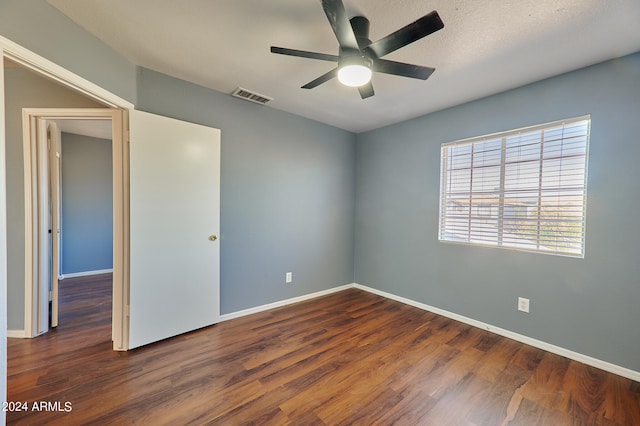 empty room with a textured ceiling, dark hardwood / wood-style flooring, and ceiling fan