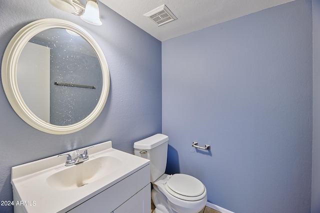 bathroom with vanity, toilet, and a textured ceiling