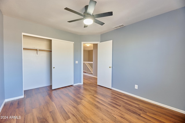 unfurnished bedroom with ceiling fan, a closet, and wood-type flooring