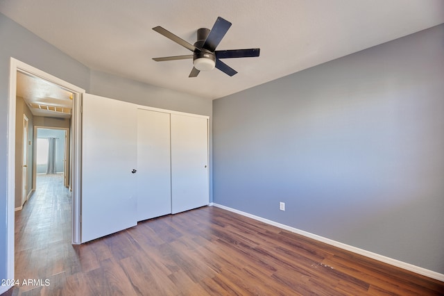 unfurnished bedroom featuring ceiling fan, dark wood-type flooring, and a closet