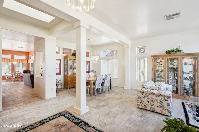 interior space with a chandelier, decorative columns, visible vents, and baseboards