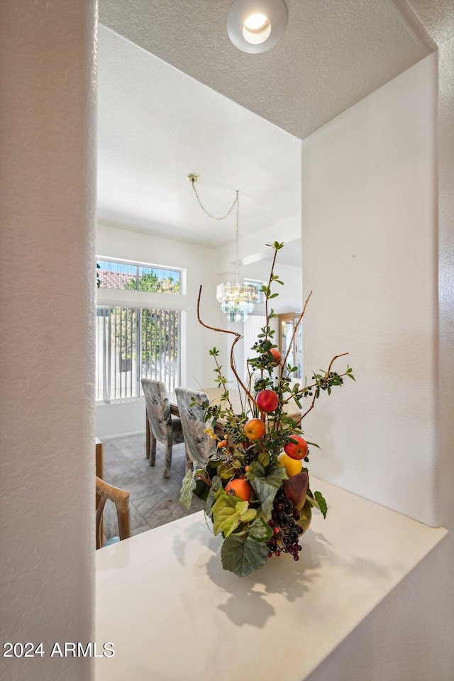 interior space featuring an inviting chandelier, a textured ceiling, and a textured wall