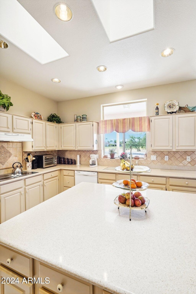 kitchen featuring a skylight, white dishwasher, light countertops, and decorative backsplash