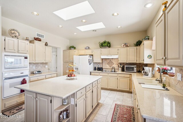 kitchen featuring white appliances, a kitchen island, under cabinet range hood, open shelves, and a sink