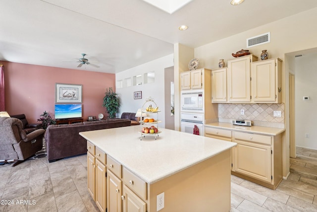 kitchen featuring white appliances, decorative backsplash, a kitchen island, open floor plan, and light countertops