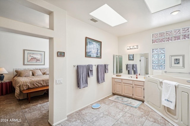 ensuite bathroom featuring a skylight, visible vents, connected bathroom, tile patterned flooring, and vanity