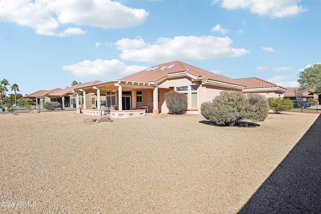 view of front of property featuring a tile roof, fence, a patio, and stucco siding