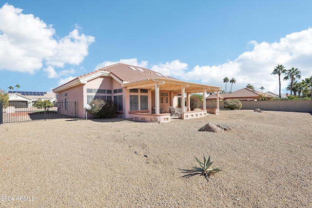 rear view of property featuring a tiled roof, a patio area, fence, and stucco siding