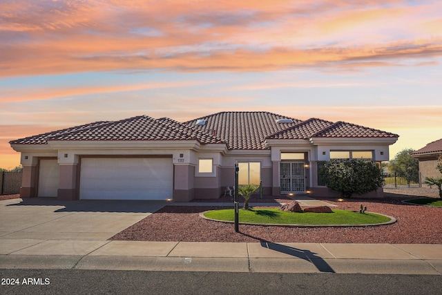 view of front of property featuring driveway, a tiled roof, an attached garage, and stucco siding