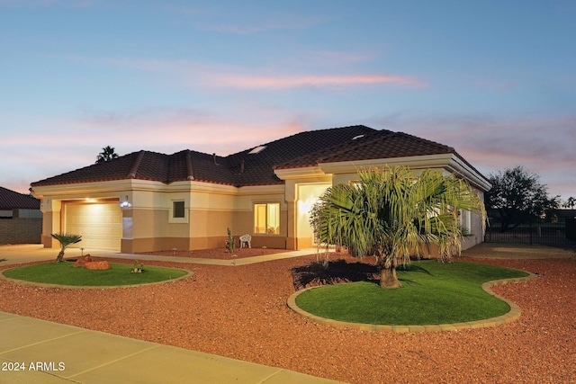 view of front of home featuring driveway, a tiled roof, an attached garage, and stucco siding