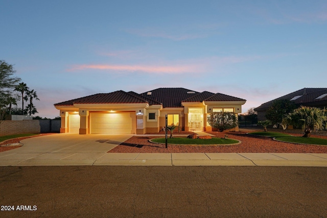 view of front of house featuring stucco siding, an attached garage, fence, driveway, and a tiled roof