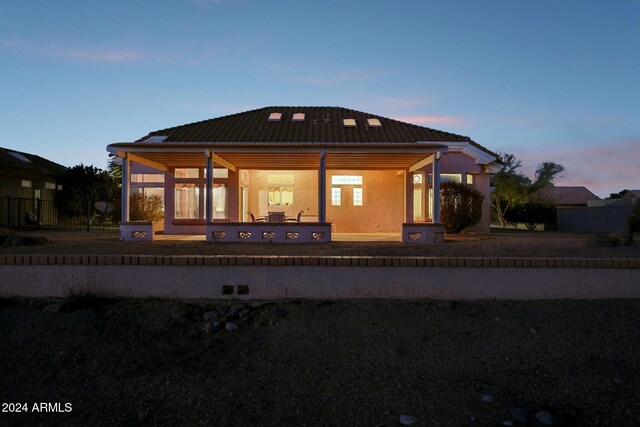 back of property at dusk featuring a patio and a tiled roof