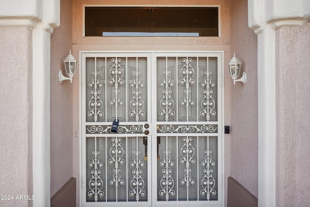 view of exterior entry featuring a gate and stucco siding