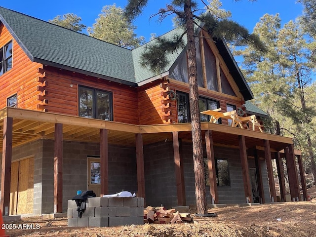 rear view of house featuring roof with shingles and log siding