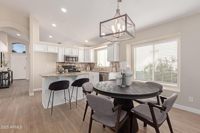 dining space featuring light wood-type flooring, sink, and a chandelier