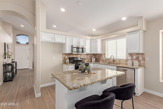 kitchen with a kitchen island, decorative backsplash, sink, white cabinetry, and appliances with stainless steel finishes