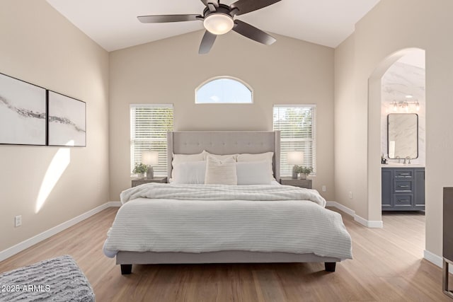 bedroom with ceiling fan, connected bathroom, light hardwood / wood-style flooring, and high vaulted ceiling