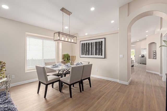 dining area with light wood-type flooring, vaulted ceiling, and a wealth of natural light