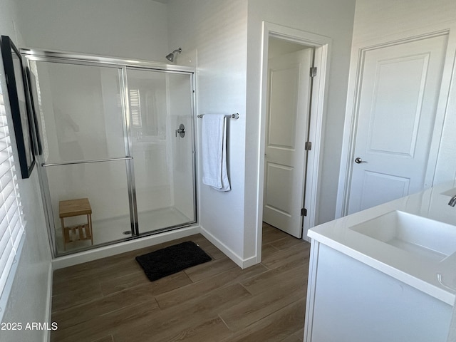 bathroom featuring a shower with door and vanity