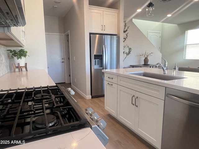 kitchen with sink, stainless steel appliances, light hardwood / wood-style flooring, and white cabinetry