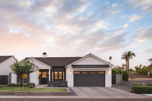 modern farmhouse style home with decorative driveway, board and batten siding, a standing seam roof, metal roof, and a garage