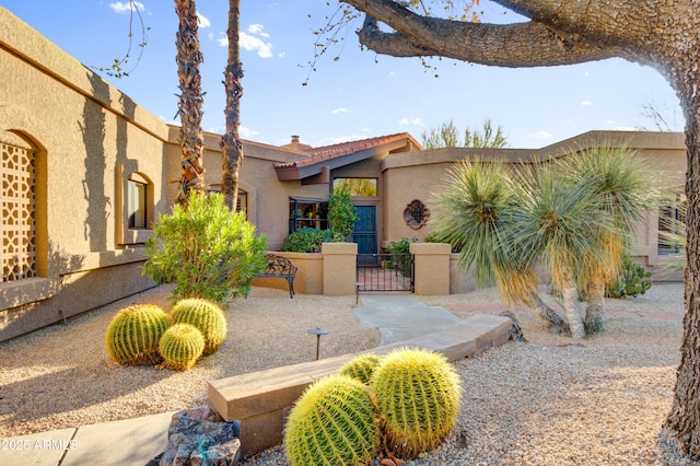 view of front facade with a chimney, fence, a gate, and stucco siding