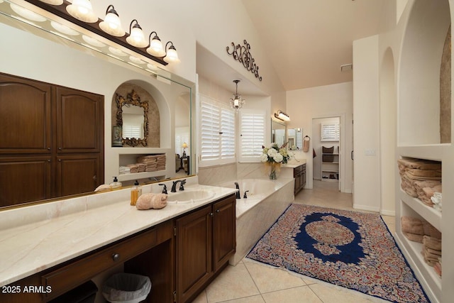 bathroom with vaulted ceiling, vanity, a bath, and tile patterned floors