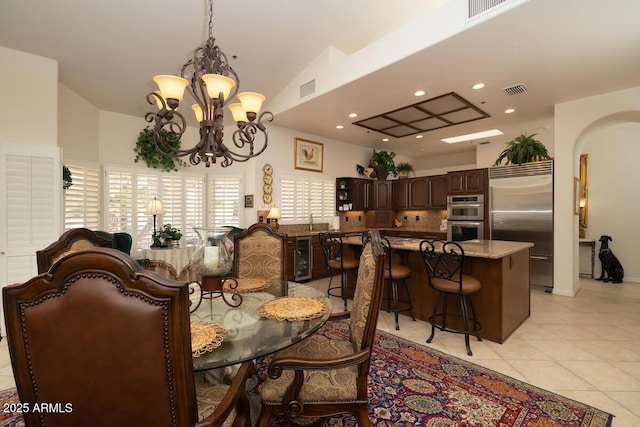 dining area featuring arched walkways, light tile patterned floors, wine cooler, and visible vents